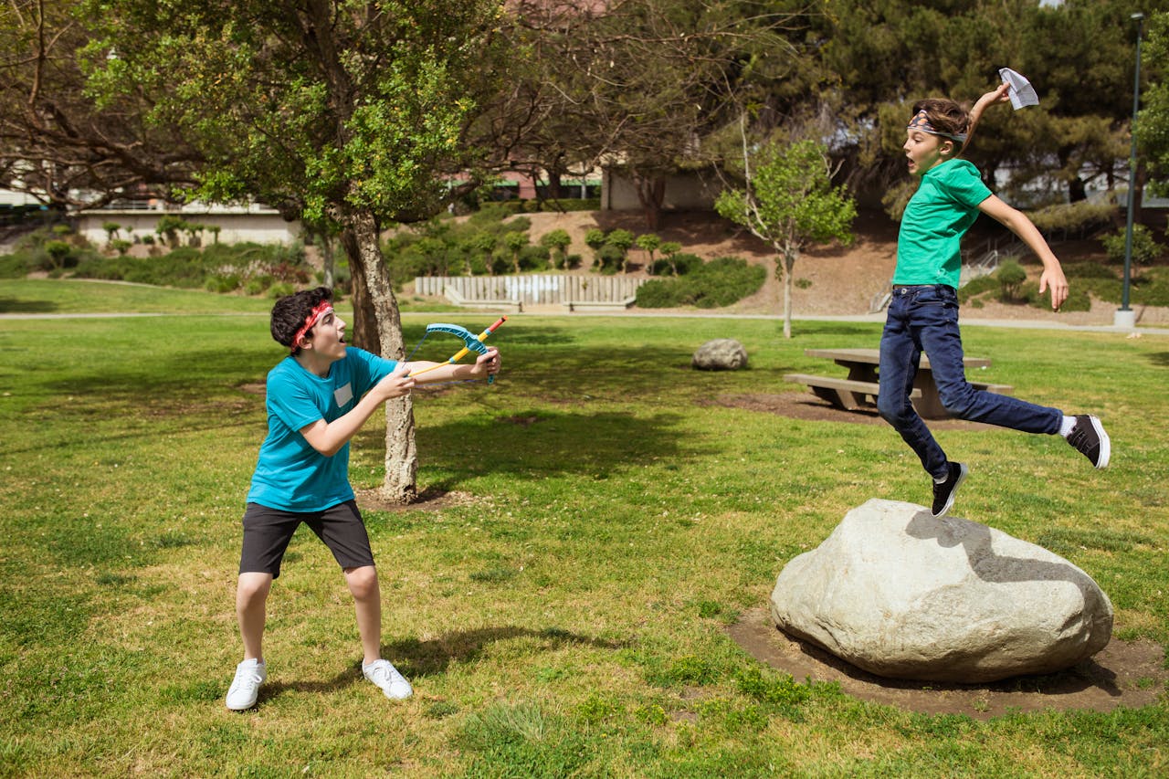 Contact Two boys having fun and playing games outdoors during summer camp.